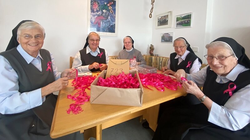 Foto: Die Ordensschwestern haben in liebevoller Handarbeit knapp 1.000 rosa Schleifen hergestellt, damit alle Mitarbeitenden Herz und Solidarität für die „Aktion Pink“ zeigen können (Bild: Alexandra Janiel).