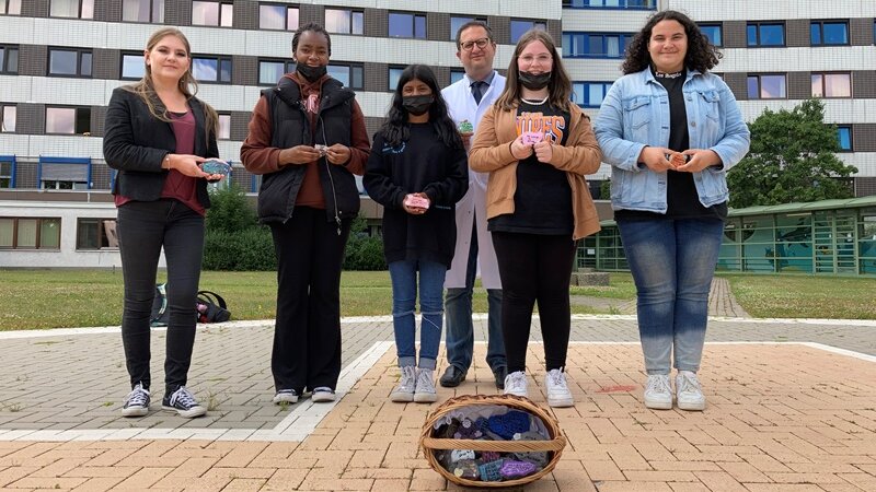 Foto: Stellvertretend für den Profilkurs „Sozial genial“ übergaben Emanuela, Archana, Mary-Jane und Kimberley mit Lehrerin Jenny Schlüter von der Arnold-Freymuth-Gesamtschule individuell bemalte Glückssteine für Krebspatienten des EVK Hamm (Foto: EVK Hamm / Carolin Drees)